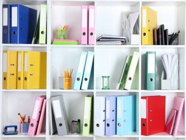White office shelves with folders and different stationery, close up