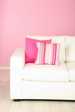 Odada pembe bir arka plan üzerinde beyaz kanepe yakın çekim