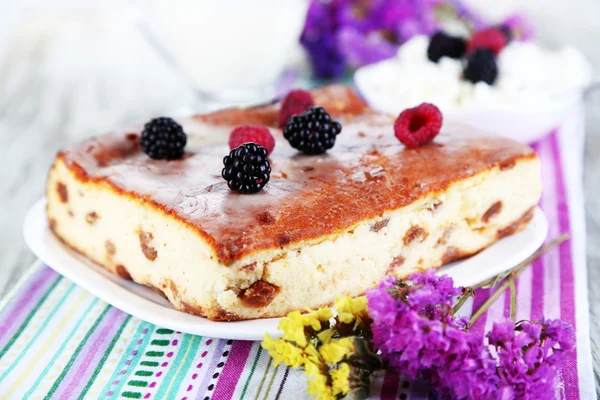 Cheese casserole with raisins on plate on napkin on wooden table close-up — Stock Photo, Image