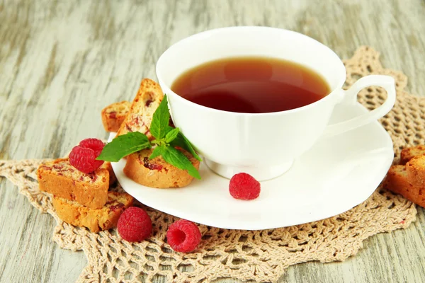 Filiżanka herbaty z ciasteczka i malin na stół szczegół — Zdjęcie stockowe