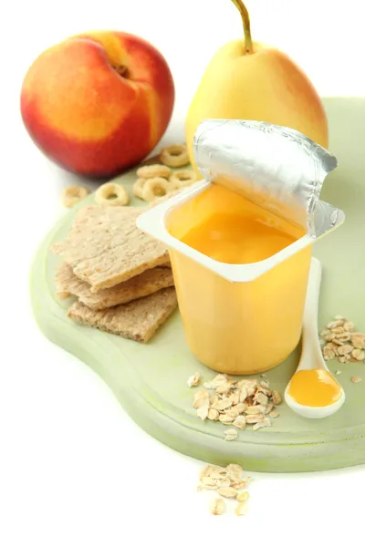 Läckra yoghurt i öppna plastmugg, kakor och frukt, trä ombord, isolerad på vit — Stockfoto