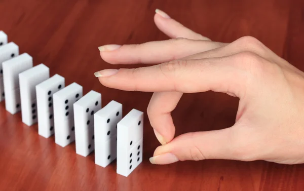 Hand pushing dominoes on wooden background — Stock Photo, Image