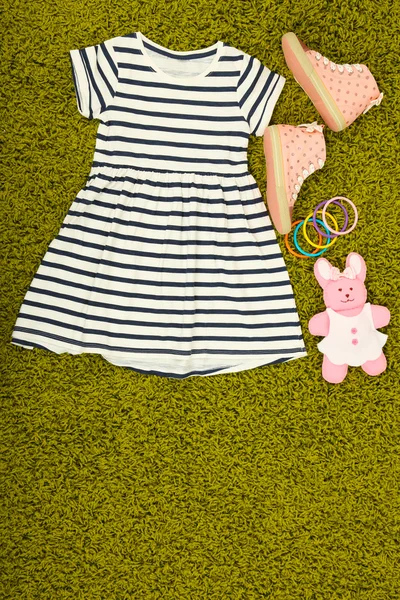 Schönes Kleid und Gummischuhe für kleines Mädchen auf grünem Teppich — Stockfoto