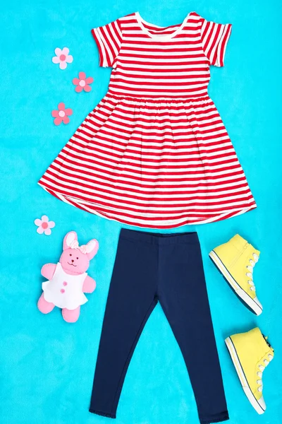 Красивая одежда для маленькой девочки на синем фоне — стоковое фото