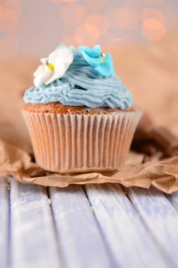 Işıklar arka plan üzerinde renkli ahşap masa üzerine tereyağı krema ile lezzetli kek