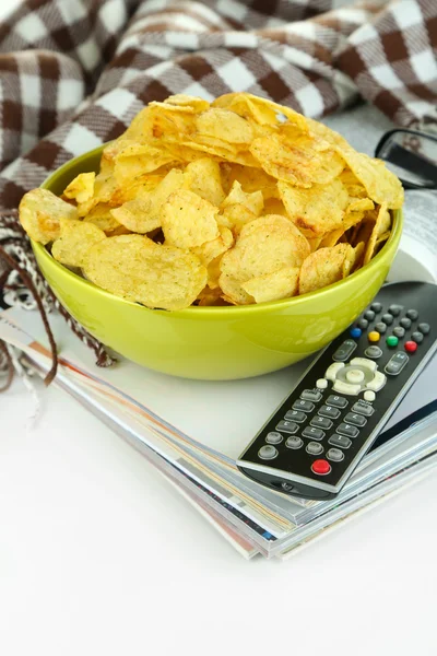 Chips in ciotola e telecomando isolato su bianco — Foto Stock