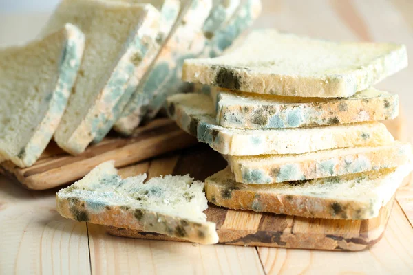 Mögligt bröd på skärbräda, på trä bakgrund — Stockfoto