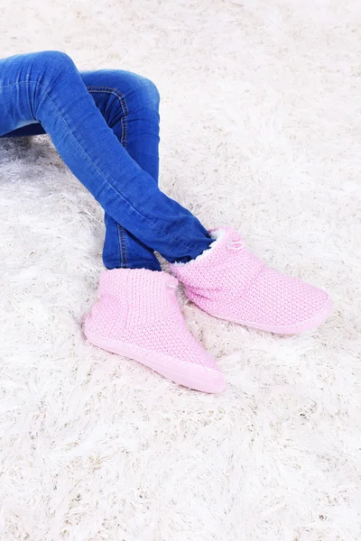 Female legs in blue jeans trousers and home winter shoes, on white carpet background — Stock Photo, Image