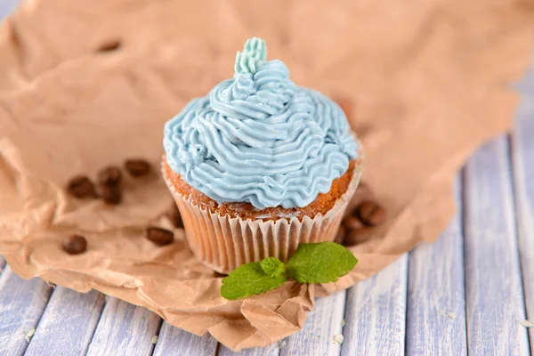 Tasty cupcake with butter cream, on color wooden background — Stock Photo, Image