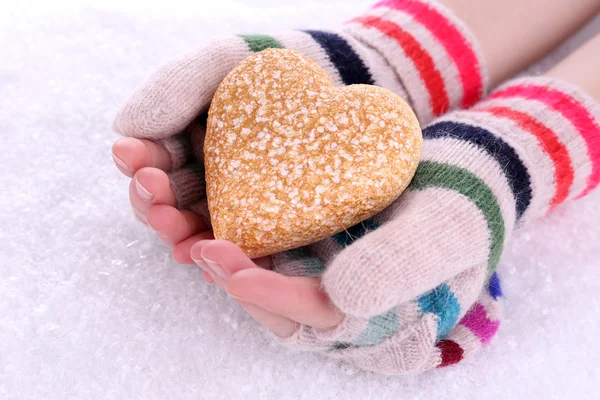 Manos femeninas en manoplas con corazón sobre fondo de nieve — Foto de Stock