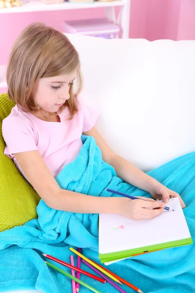 Little girl draws sitting on sofa in room — Stock Photo, Image