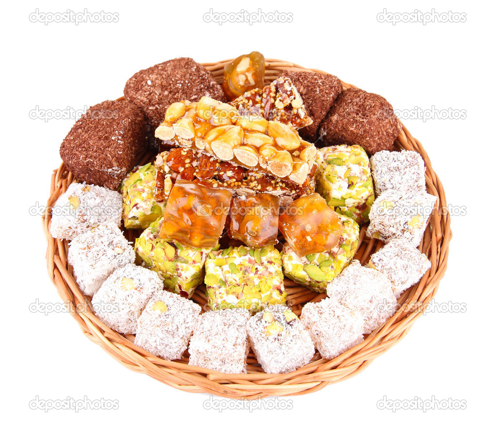 Tasty oriental sweets on wicker tray, isolated on white