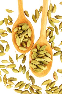 içinde tahta kaşıklar üzerinde beyaz arka plan yakın çekim yeşil kakule