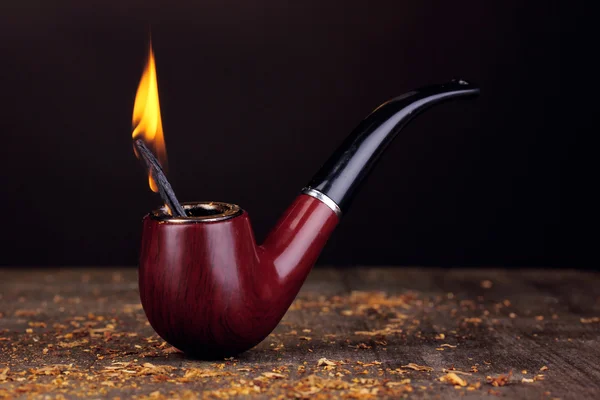 Smoking pipe and tobacco on wooden table on black background — Stock Photo, Image