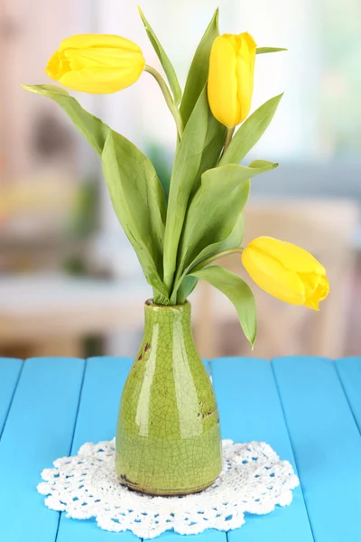 Tulipas amarelas em vaso na mesa de madeira no fundo do quarto — Fotografia de Stock