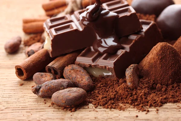 Composizione di caramelle al cioccolato, cacao e spezie su fondo di legno — Foto Stock