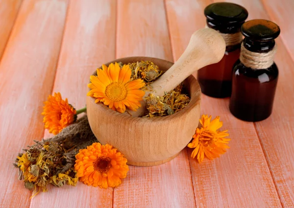 Geneeskundeflessen en calendula bloemen op houten achtergrond — Stockfoto