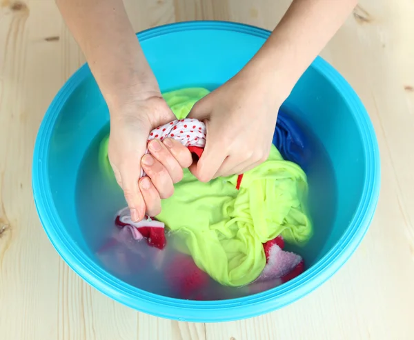 Hand washing in plastic bowl on wooden table close-up — Stock Photo, Image