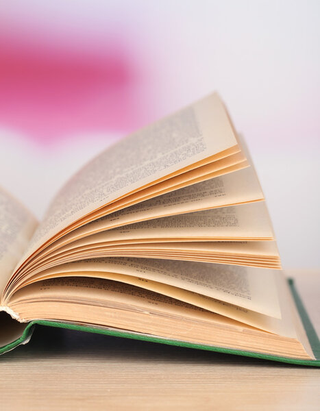 Открытая книга на деревянном столе на ярком фоне
