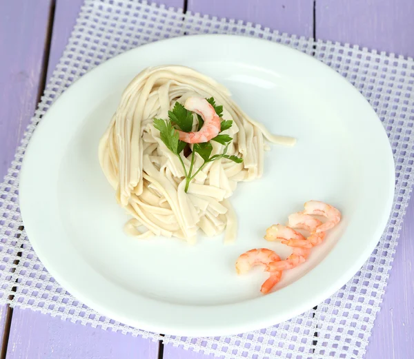 Pasta with shrimps on white plate, on wooden background — Stock Photo, Image