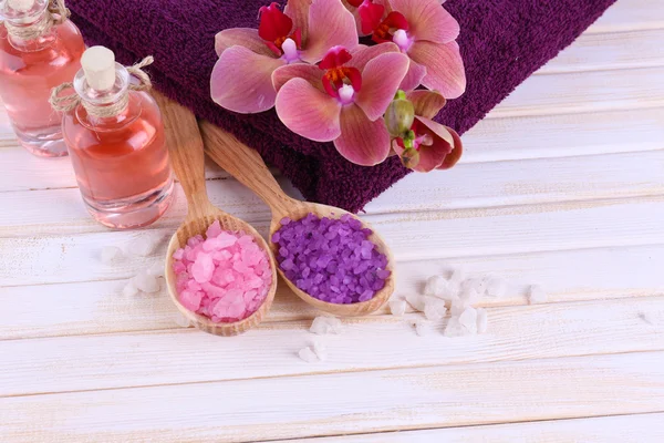 Bodegón con hermosa flor de orquídea y cucharas de madera con sal marina, sobre fondo de madera de color —  Fotos de Stock