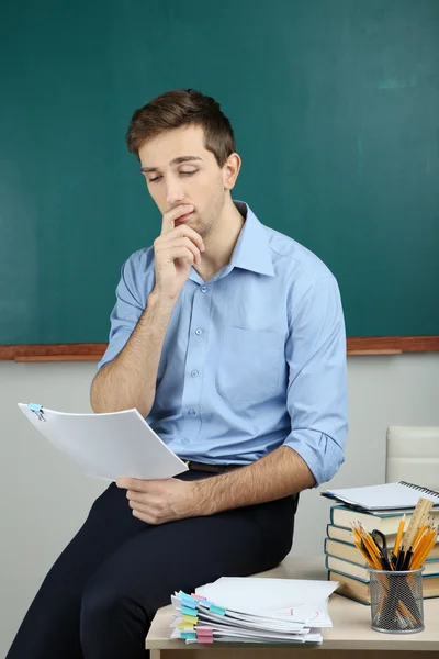 Junge Lehrerin sitzt auf Schreibtisch im Klassenzimmer — Stockfoto