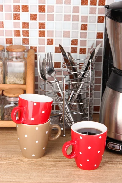 Kopjes en koffie-/ theevoorzieningen in keuken op tafel op mozaïek tegels achtergrond — Stockfoto