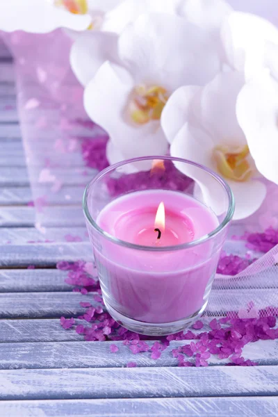Schöne bunte Kerzen und Orchideenblumen, auf farbigem Holzgrund — Stockfoto