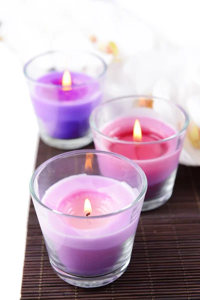 Composición con hermosas velas de colores, sal marina y flores de orquídea, sobre estera de bambú, sobre fondo claro — Foto de Stock