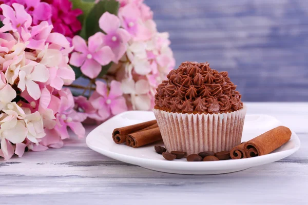 Smakelijke cupcake met boter room, op de plaat, op een houten achtergrond kleur — Stockfoto