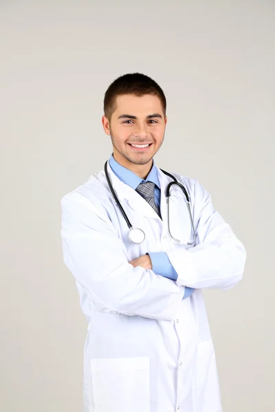 Αρσενικό Γιατρός στέκεται σε γκρι φόντο — Φωτογραφία Αρχείου