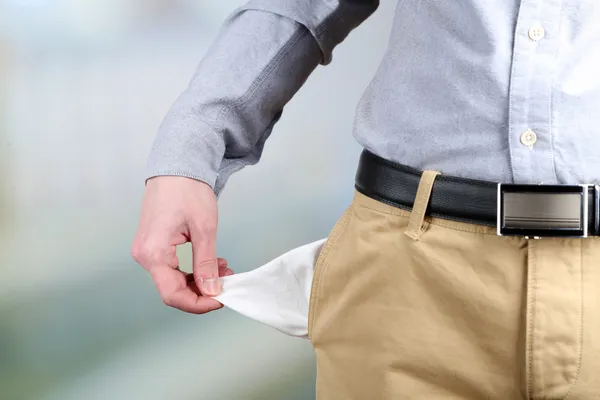 Homem mostrando seu bolso vazio no fundo brilhante — Fotografia de Stock