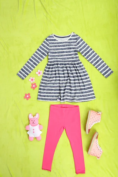 Schöne Kleidung für kleines Mädchen auf grünem Hintergrund — Stockfoto