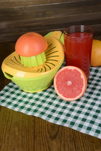 Цитрусовый пресс и грейпфруты на столе на деревянном фоне — стоковое фото
