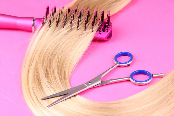 Lange blonde Haare mit Haarbürste und Schere auf rosa Hintergrund — Stockfoto