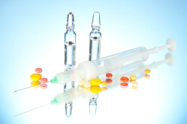 Syringe monovet, ampoules and pills on blue background — Stock Photo, Image