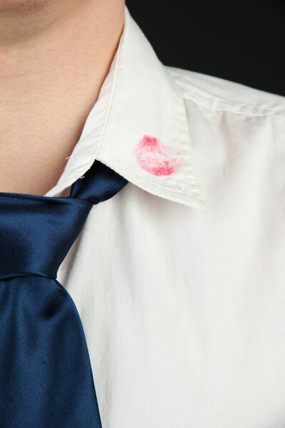 Lipstick kiss on shirt collar of man, isolated on black