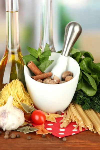 Composition of mortar, pasta and green herbals, on bright background — Stock Photo, Image