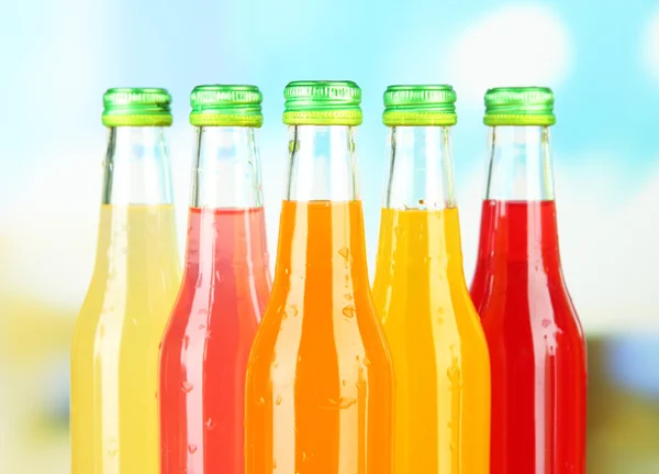 Bottiglie con gustose bevande su sfondo luminoso — Foto Stock