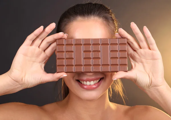 Retrato de menina bonita com chocolate no fundo marrom — Fotografia de Stock