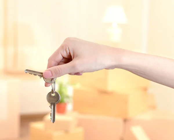 Kvinnlig hand med nycklar ob stack av kartonger bakgrunden: flyttar house koncept — Stockfoto