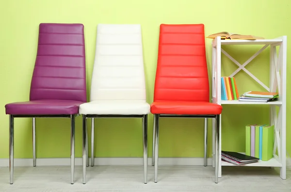 Vacker interiör med modern färg stolar, böcker på monter, på vägg bakgrund — Stockfoto
