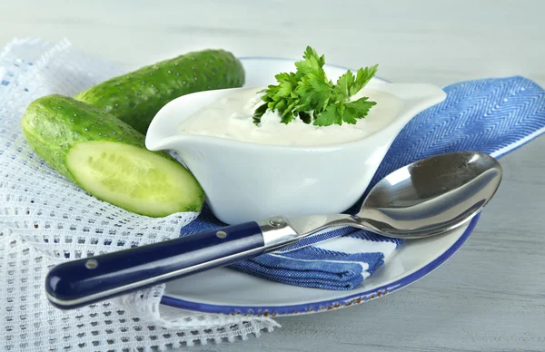 Cucumber yogurt in sauceboat, on color napkin, oncolor wooden background — Stock Photo, Image