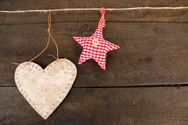 Декоративное сердце и звезда на веревке, на сером деревянном фоне — стоковое фото