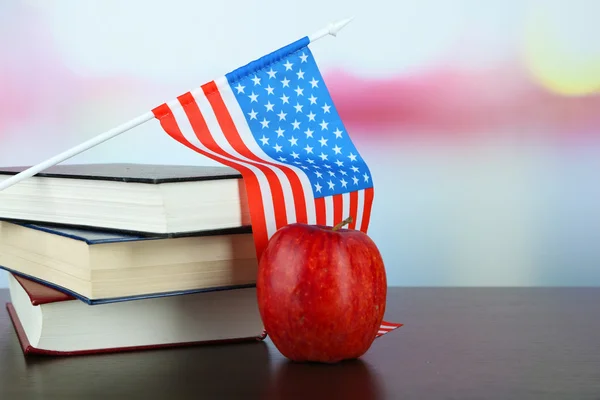 Composición de la bandera americana, libros y manzana sobre mesa de madera, sobre fondo claro — Foto de Stock