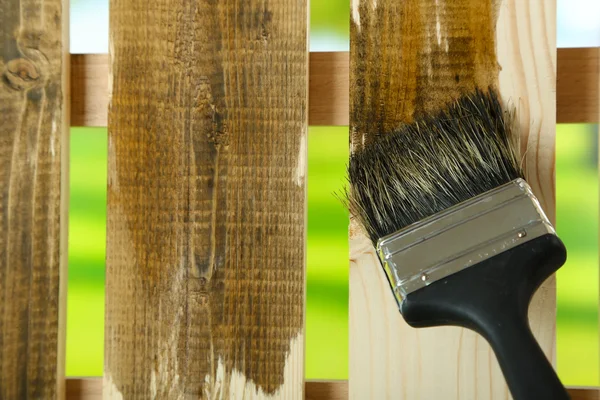 Applicando vernice protettiva alla recinzione di legno, su sfondo luminoso — Foto Stock