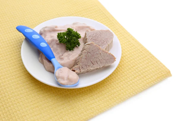М'ясна паста для годування немовлят, на тарілці, на кольоровій серветці, ізольована на білому — стокове фото