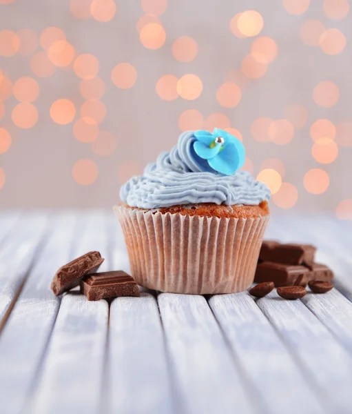 Finom cupcake vaj tejszín, színes fából készült asztal, fények háttér — Stock Fotó