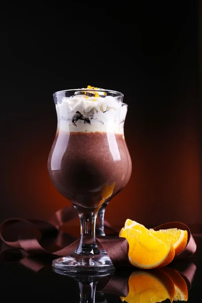 Sobremesa saborosa com chocolate, creme e molho de laranja, no fundo de cor escura — Fotografia de Stock