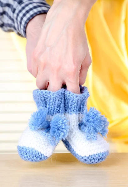 Mãos com botas de malha para bebê, no fundo claro — Fotografia de Stock